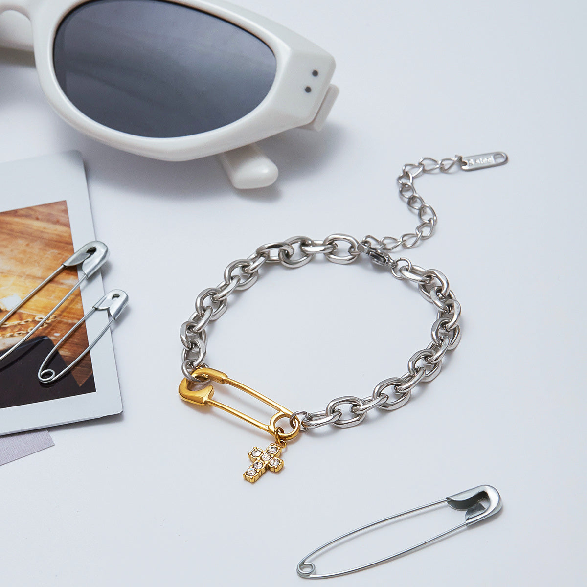 Side-by-side view of a safety pin link bracelet with pvd gold plated cross charm and a zircon stone bracelet styled on a feminine wrist, ideal for fashion-forward jewelry lovers.