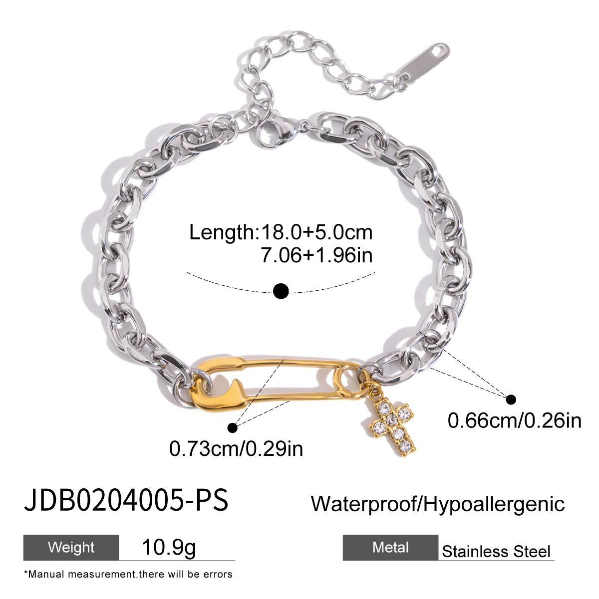 Flat lay of a two tone safety pin link chain bracelet with a zircon stone studded cross charm, perfect as a link chain bracelet for men or women in high-end fashion collections.