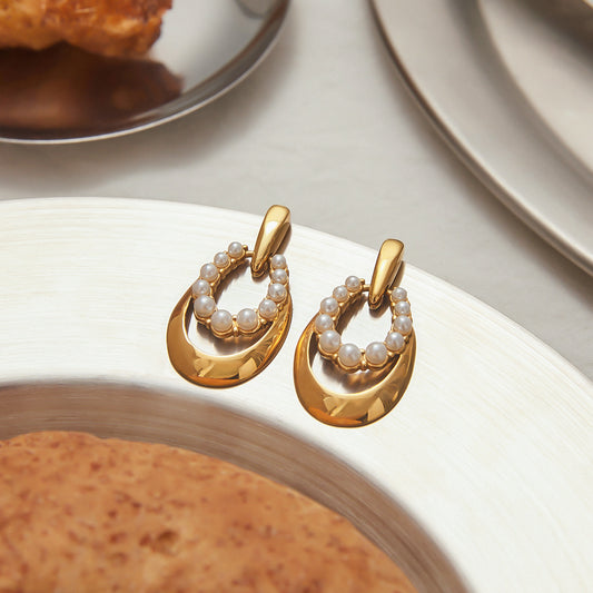 Set of pvd gold plated pearl earrings displayed on a plate. These stainless steel earrings are crafted for durability with titanium studs, offering a non tarnish and non shedding finish.