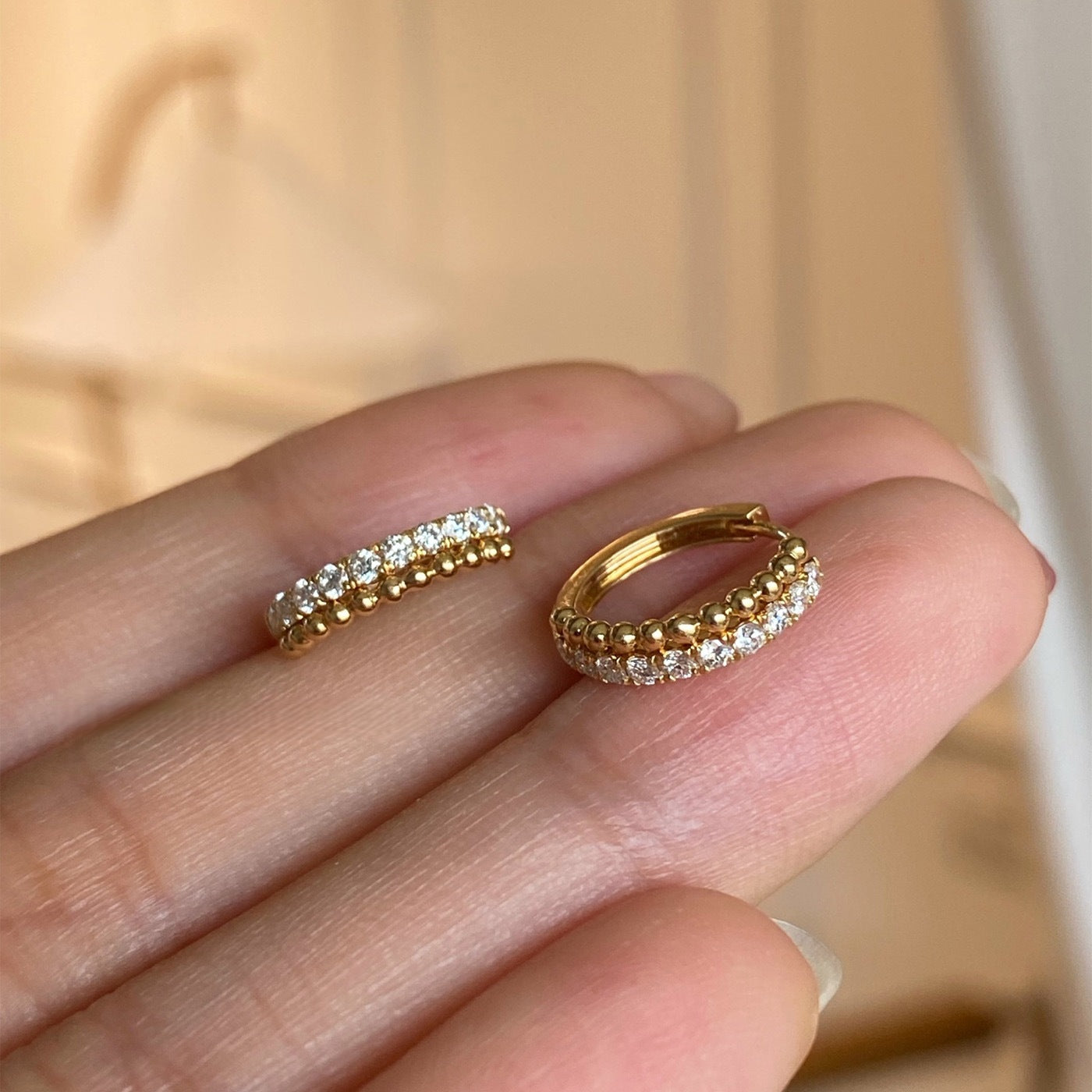 Close-up of 18k gold plated cubic zirconia beaded huggie hoops, wholesale 925 sterling silver earrings for women.
