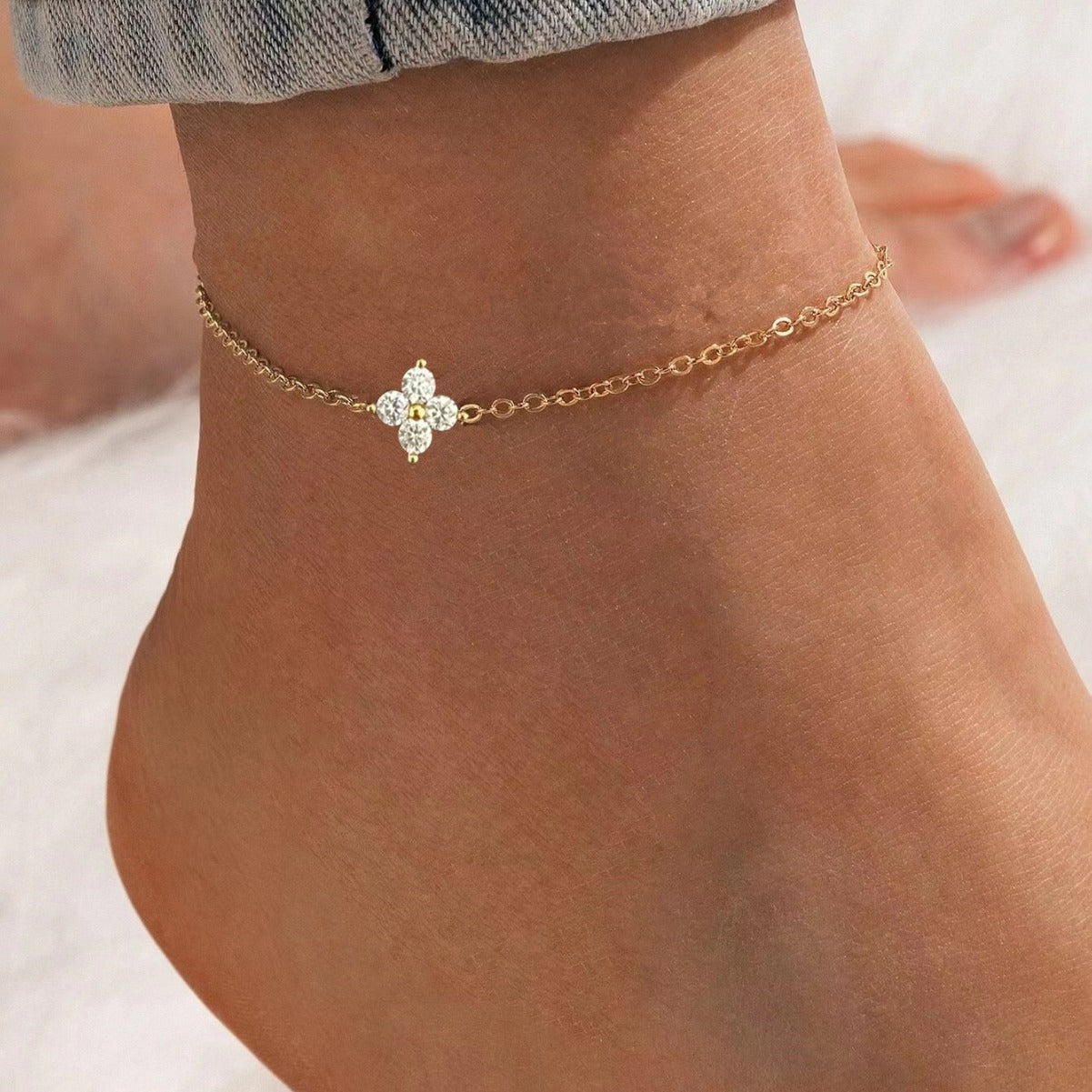 Gold plated sterling silver four leaf clover anklet displayed on model’s ankle