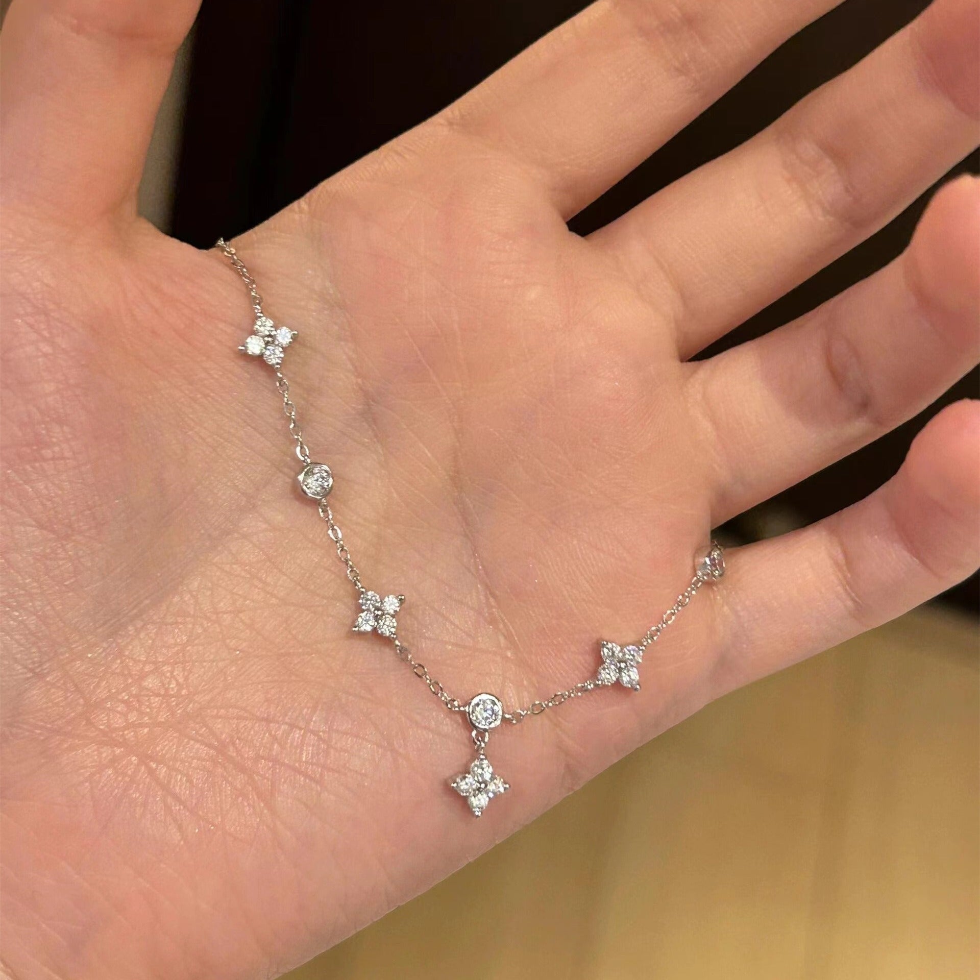 Close-up of four leaf clover anklet in solid 925 silver on sandy background