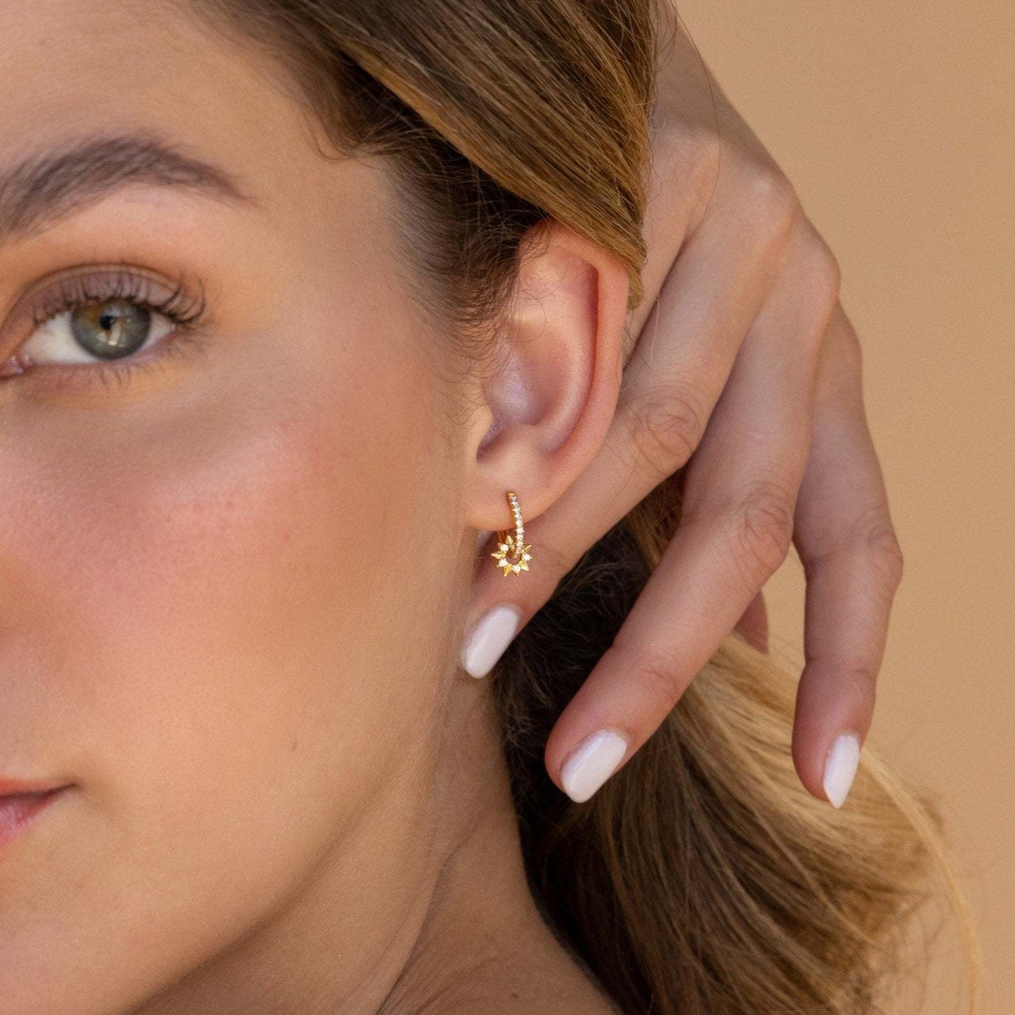 Close-up of sterling silver gold hoops with dangling five-point stars and CZ stones, perfect holiday jewelry gift