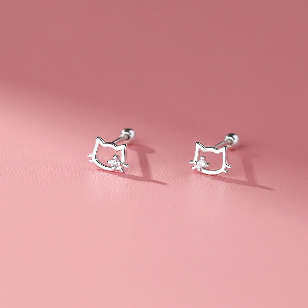 Dainty sterling silver kitten outline earrings with a central zirconia stone, shown in close-up on a jewelry tray