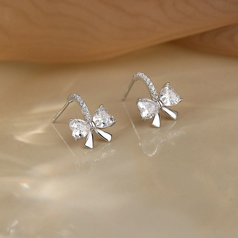 Elegant sterling silver knot-style earrings with diamond-like CZ stones, styled as a gift for women on special occasions