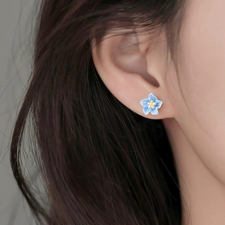 close-up of dainty blue blossom earrings with silver posts, suitable for everyday outfits
