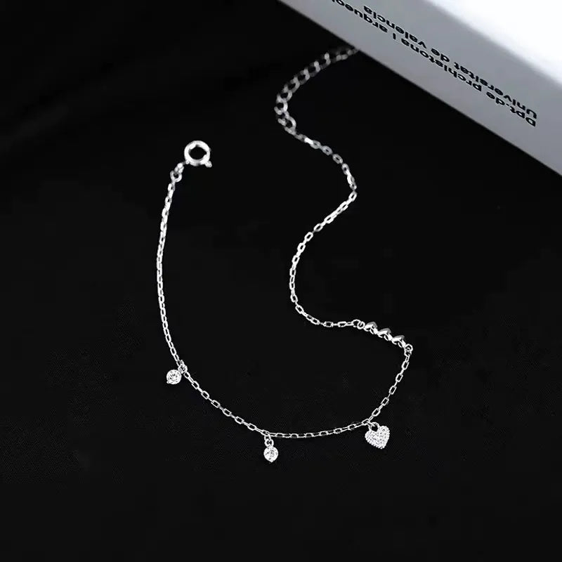 Sterling silver asymmetrical heart bracelet with pavé center and sparkling CZ dangles