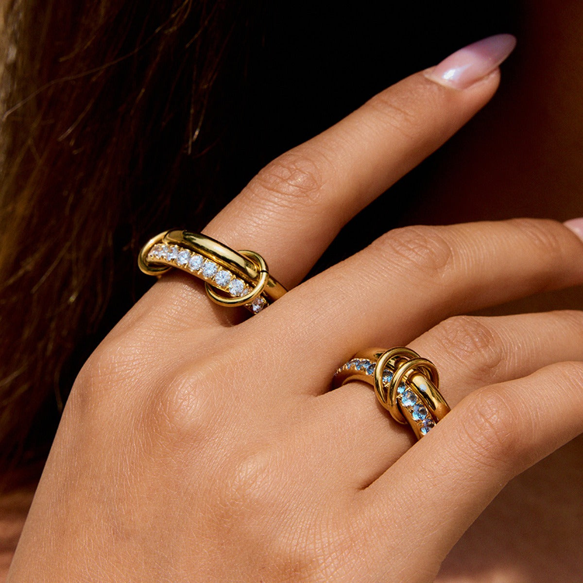 Gold PVD plated stainless steel rings worn on hand, featuring White and Blue cubic zirconia, perfect for fashion lovers
