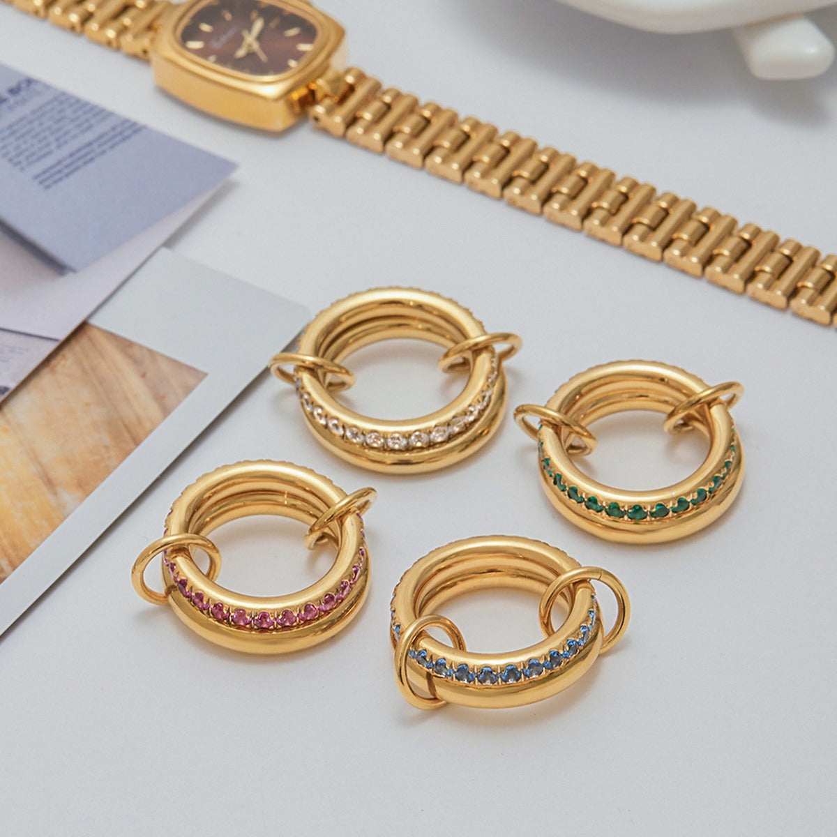 Set of four gold PVD plated stainless steel rings with cubic zirconia in white, green, pink, and blue, waterproof and hypoallergenic
