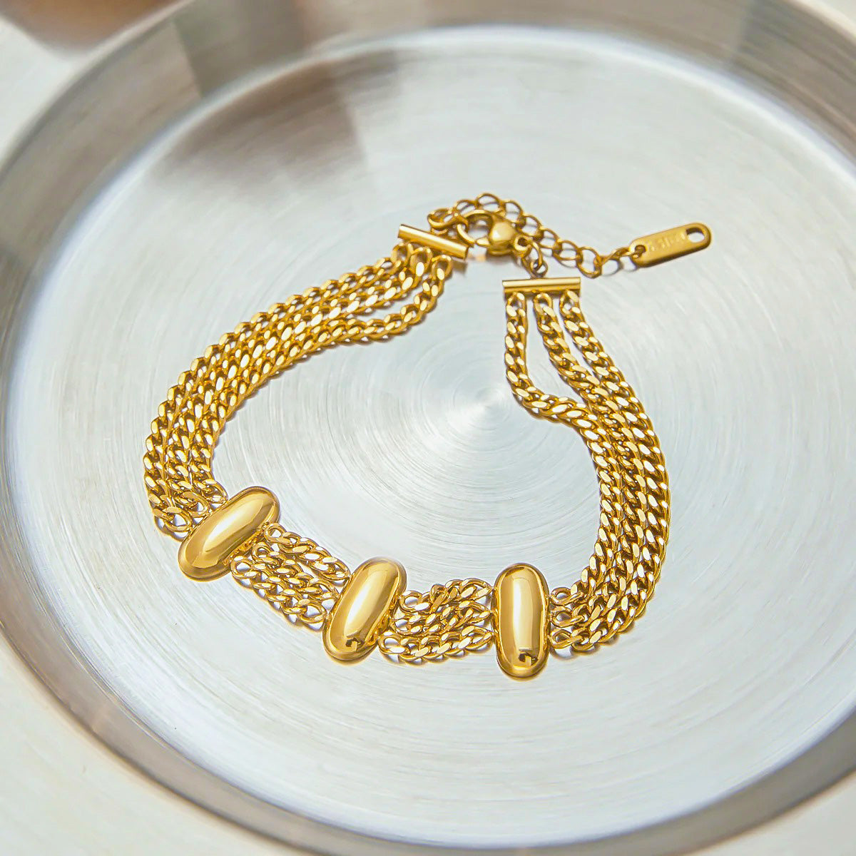 Layered Chain Gold Bracelets displayed in a silver tray, featuring the stainless steel bracelet design in a modern look for women.