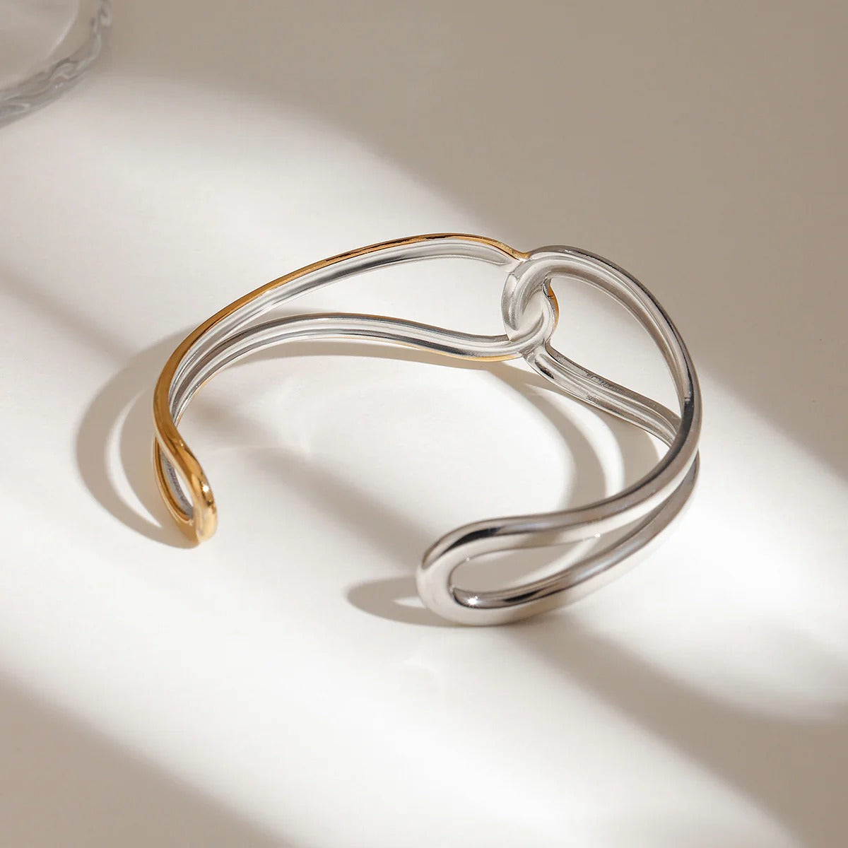A bold two tone gold and silver bracelet made from waterproof stainless steel, highlighting the flowing open cuff design — ideal for fashion-forward wholesale bangles.