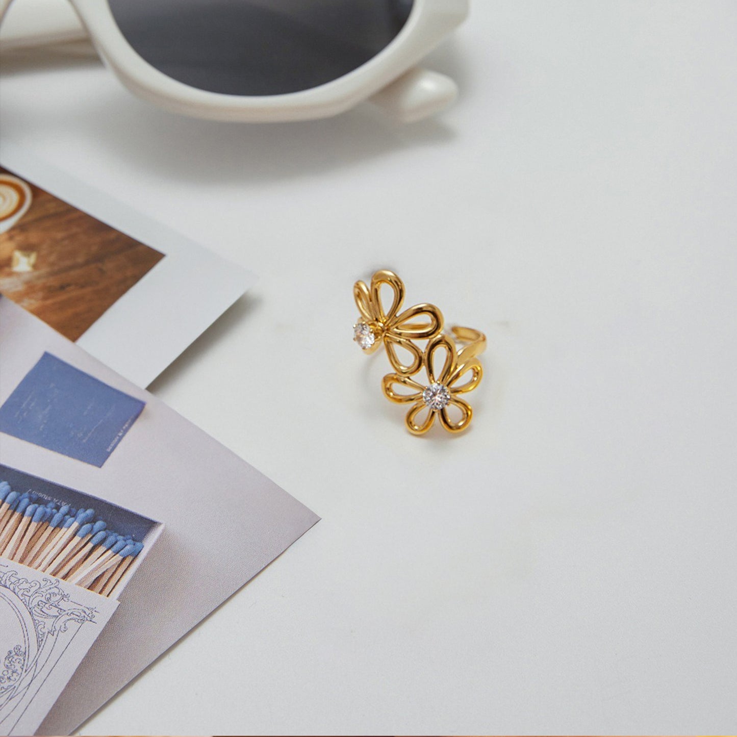 Zircon flower ring in gold titanium steel displayed with lifestyle flatlay, a delicate and lightweight jewelry piece for women.