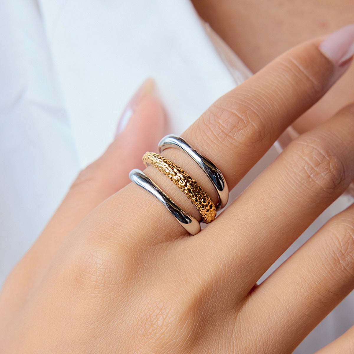 Two tone stainless steel ring with hammered gold and silver layers placed on a design magazine. Non tarnish fashion jewelry perfect for daily wear.
