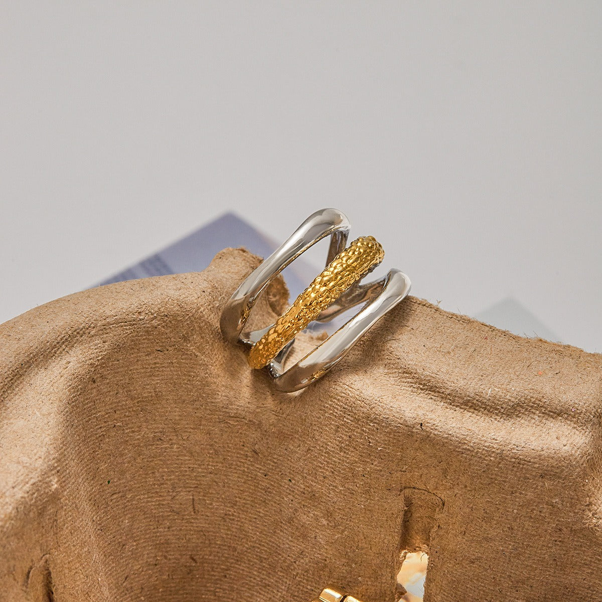 Elegant gold and silver stainless steel ring with layered textures shown with sunglasses. Two tone fashion ring ideal for everyday accessories.
