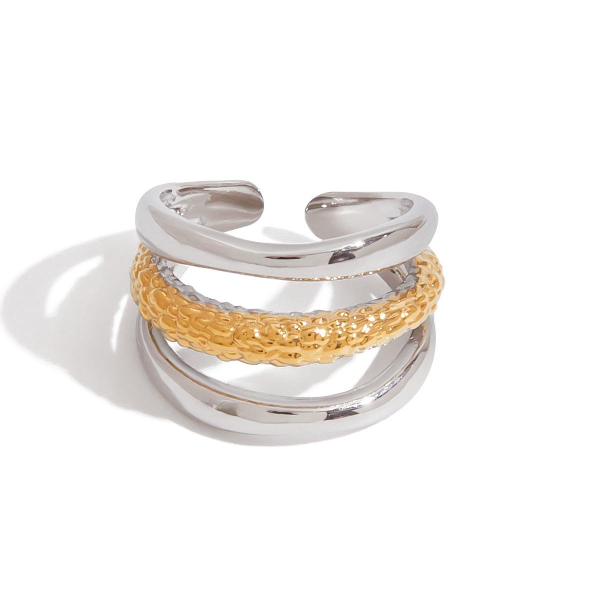 Stacked gold and silver stainless steel ring resting on neutral fabric background. Trendy two tone fashion ring for daily accessories.