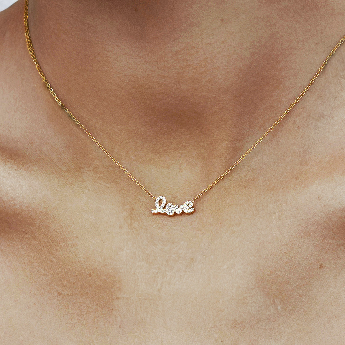 Model wearing a gold choker chain for women with a sparkling cubic zirconia love pendant. The dainty gold love necklace showcases a delicate I love you necklace for girlfriend design and makes a thoughtful Valentine's Day necklace for her