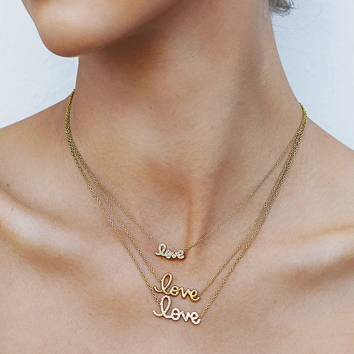 Layered shot of three gold love necklaces with letter pendants, including a cubic zirconia chain necklace and a plain gold choker chain for women. Each piece is an anti tarnish gold necklace and a sweet I love you necklace for girlfriend