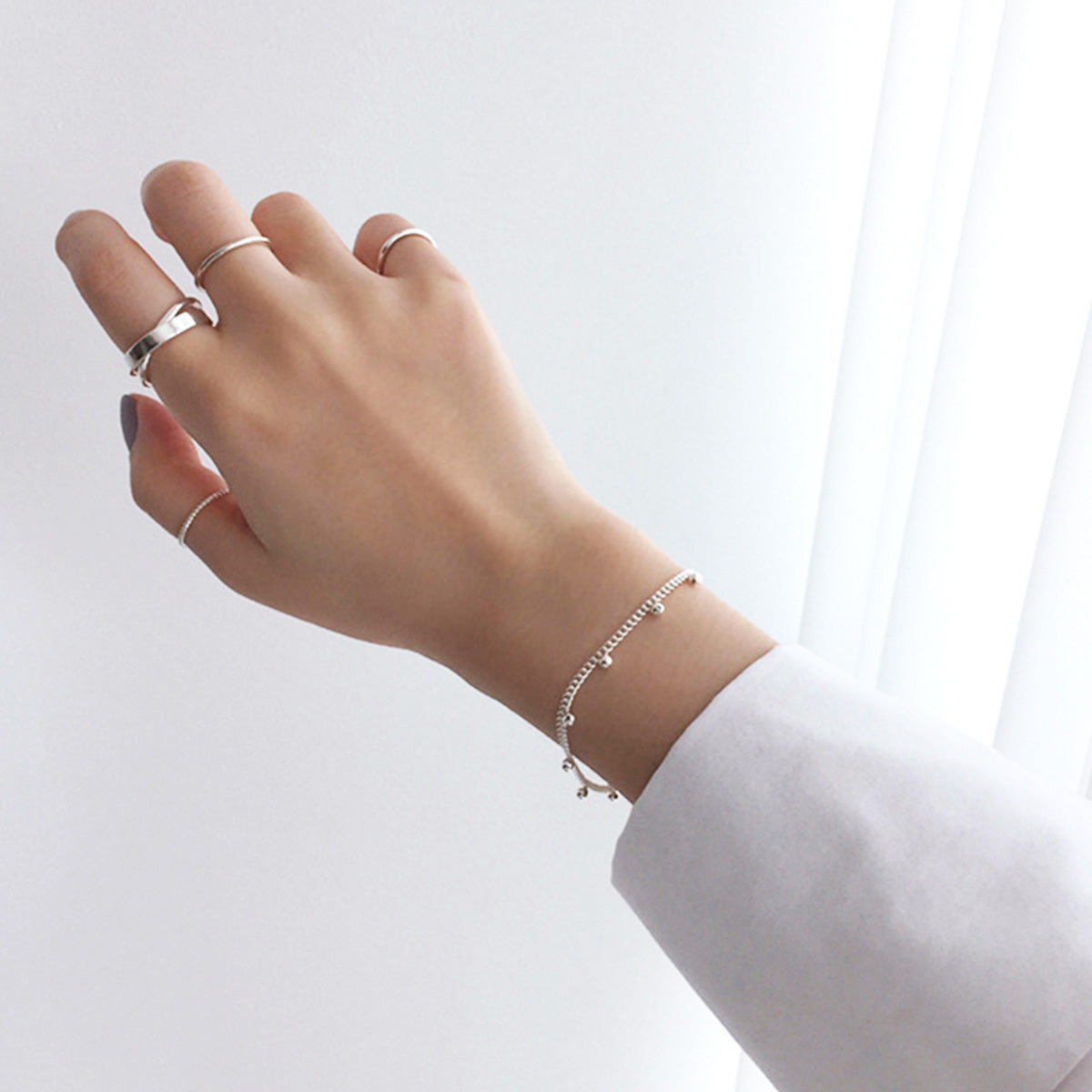 Hand wearing multiple minimalist sterling silver rings in Korean style for everyday jewelry wholesale collections
