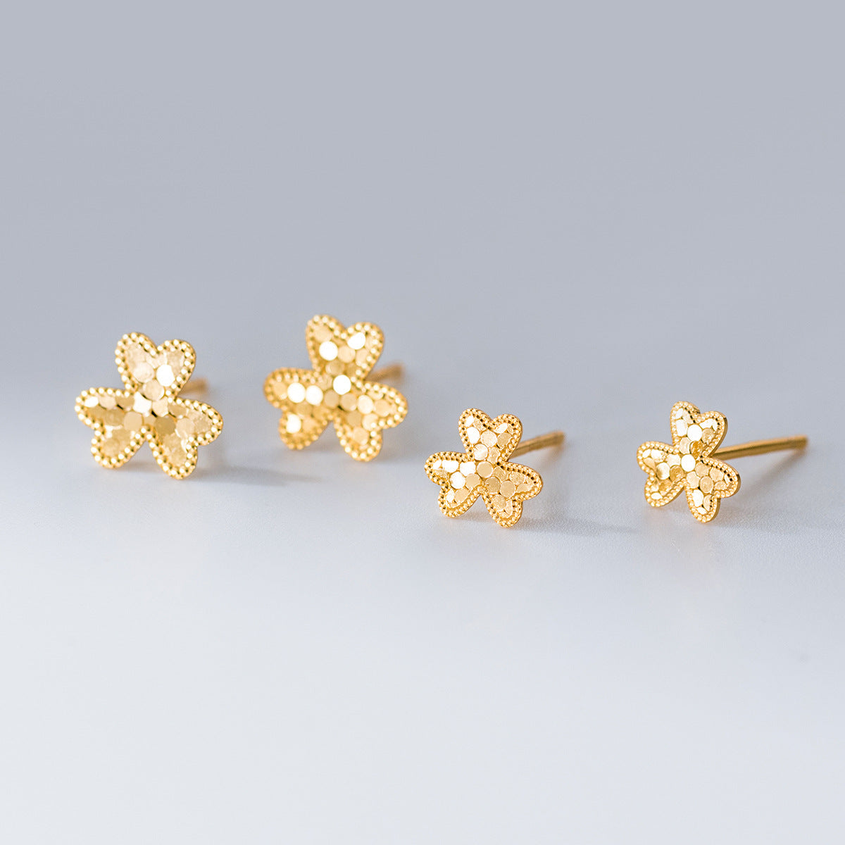 Wholesale 925 sterling silver laser cut flower stud earrings in gold, delicate floral design for bulk jewelry orders.