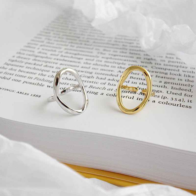 Gold and silver oval open rings placed on a book page, highlighting a set of 5 adjustable minimalist jewelry rings made for wholesale and everyday fashion collections.