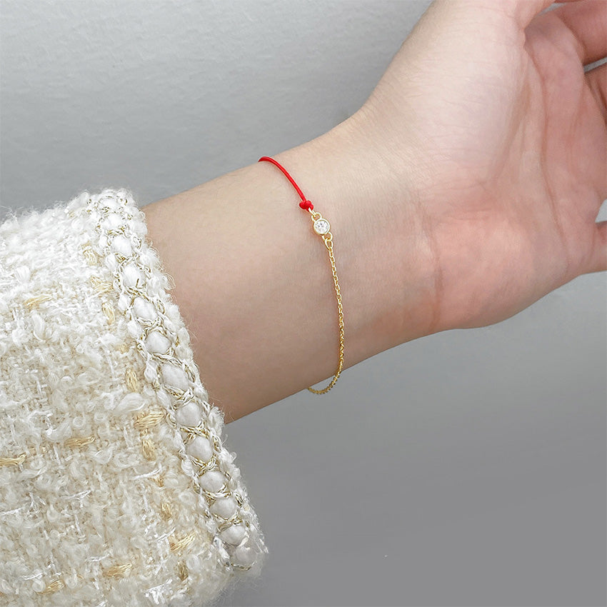 Delicate red string and gold chain cubic zirconia bracelet on wrist, perfect for everyday jewelry wholesale collections.