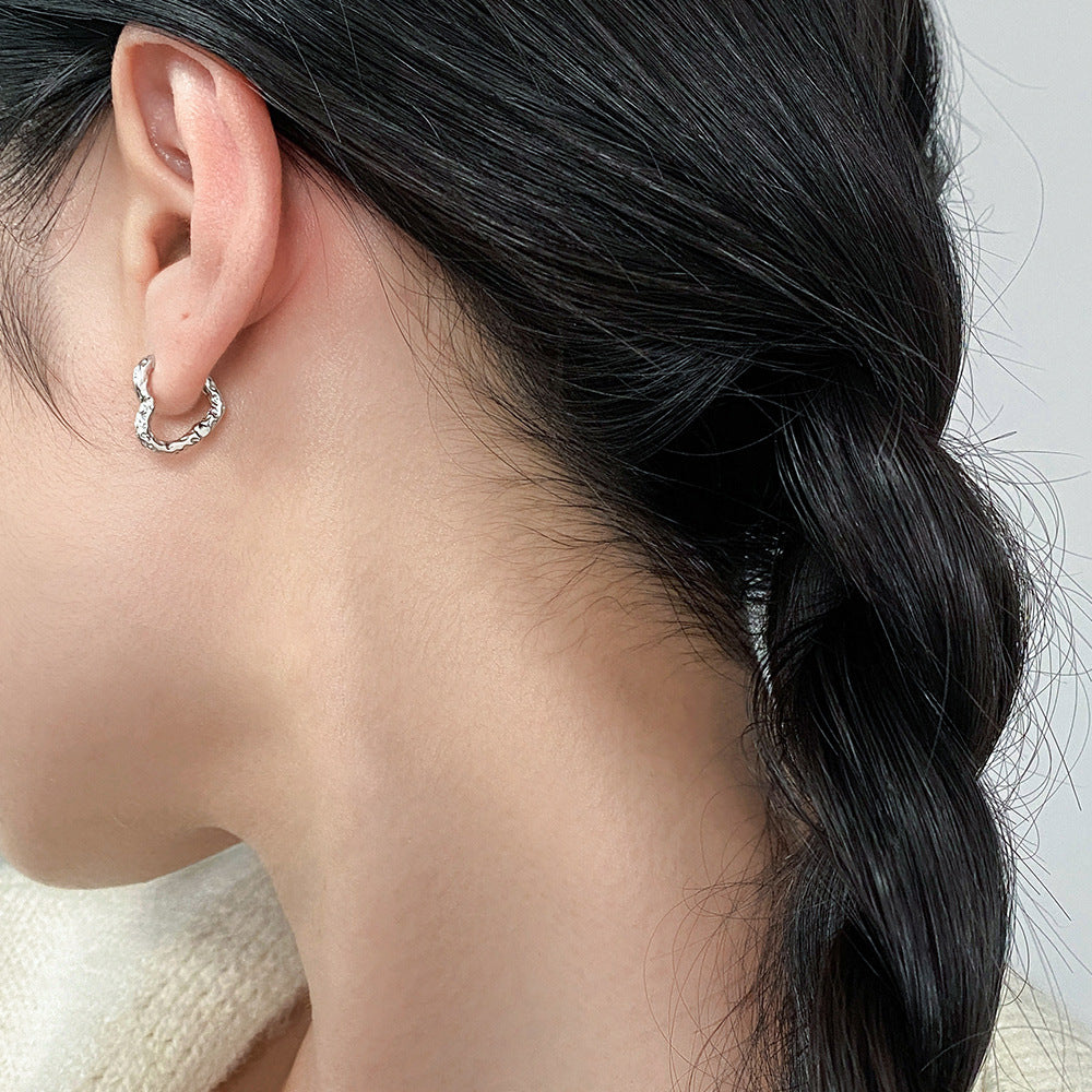 Model wearing wholesale 925 sterling silver textured heart shaped hoop earrings minimalist style
