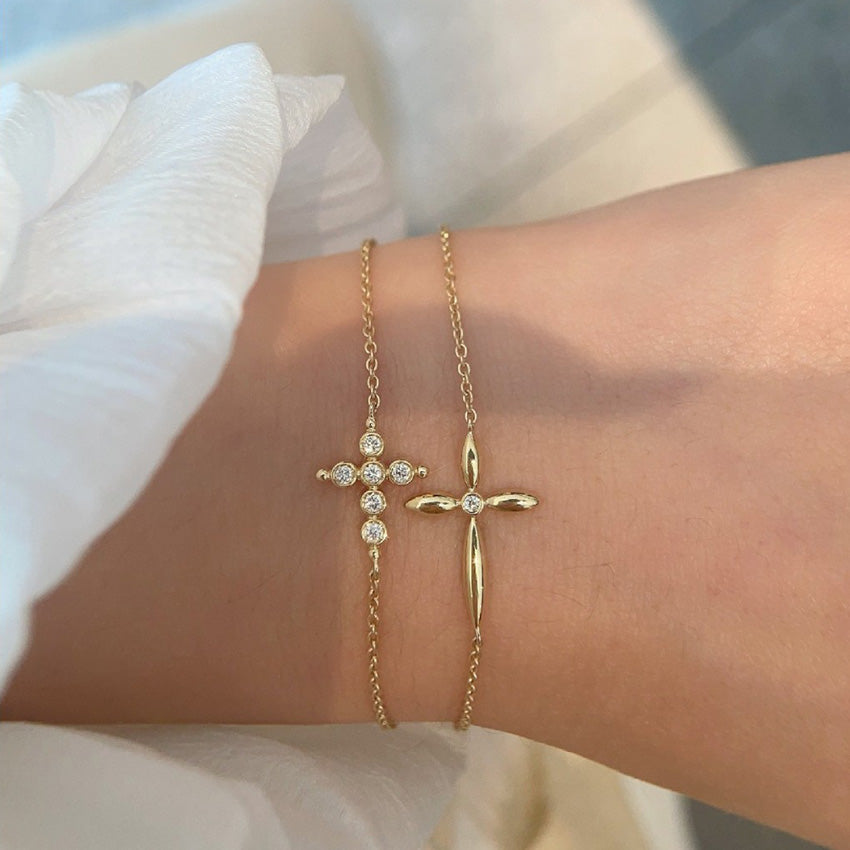 Tweezers holding gold cross charm bracelet with brilliant cz stones demonstrating premium quality for bulk purchase