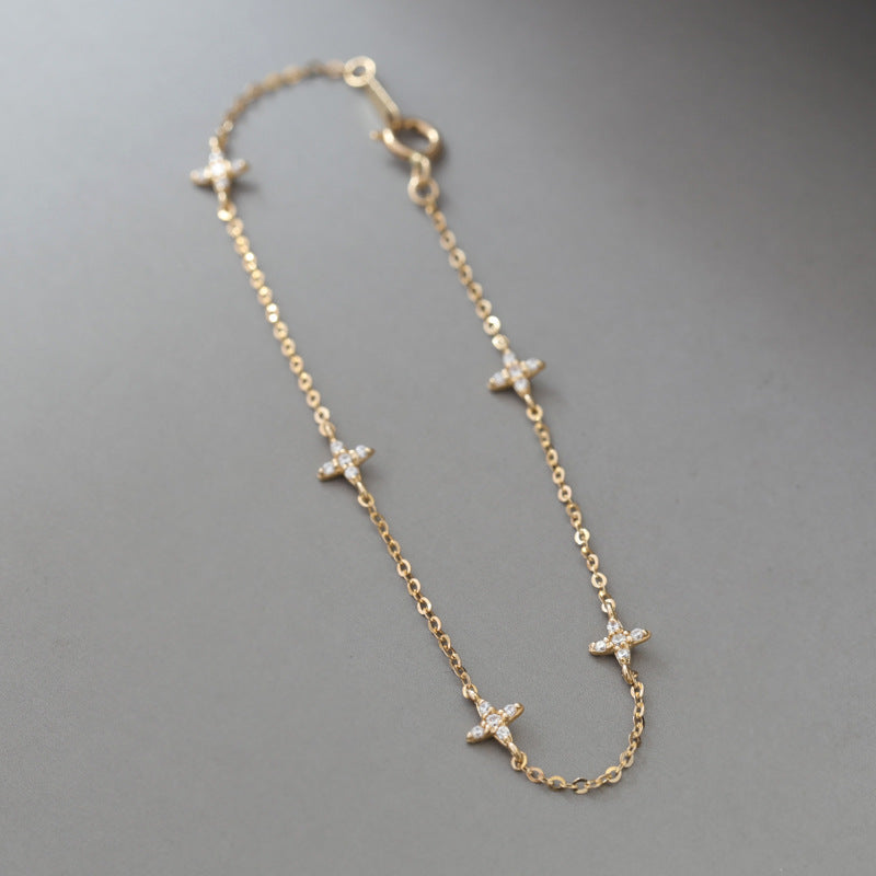 Diagonal layout of dainty gold silver star charm bracelet on gray background showing spring ring clasp