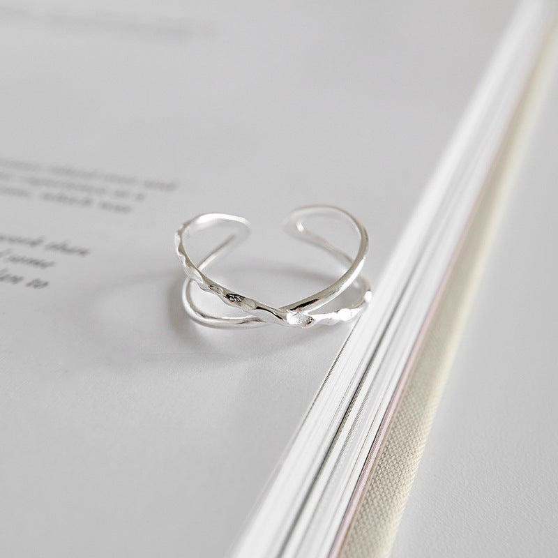 Adjustable sterling silver crossover ring displayed on book page, open ring style available for wholesale minimalist jewelry collections