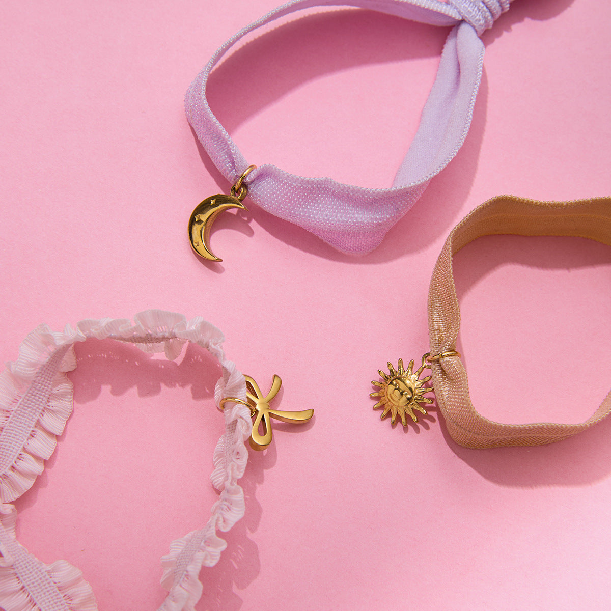 Set of 3 stainless steel charm bracelets featuring bow, sun, and moon pendants on elastic ribbon bands for wholesale jewelry