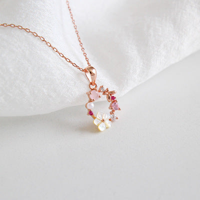 Rose gold flower necklace with pink crystal and pearl accents placed on white surface, perfect for wholesale jewelry gift sets