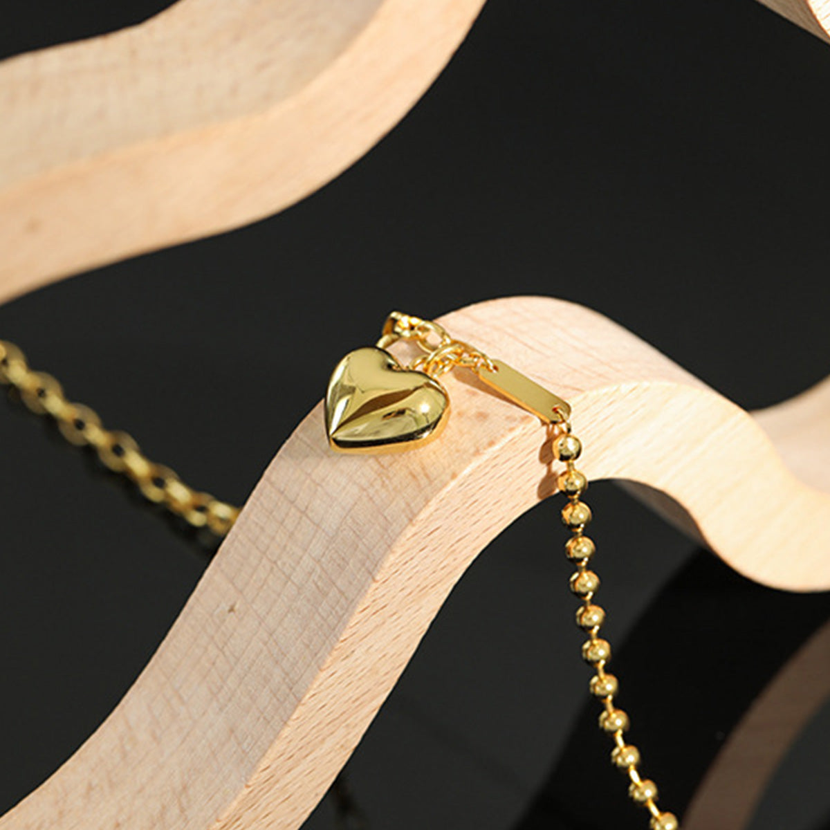 Gold heart necklace resting on wood display, a stylish choice for 925 silver jewelry wholesale and bulk gift sets.