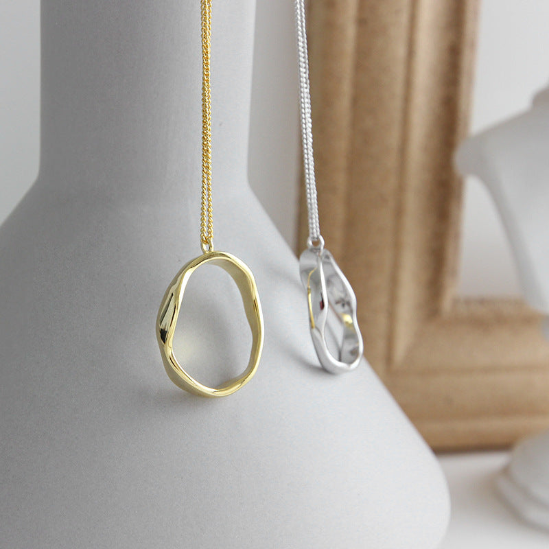 Gold irregular oval pendant necklace displayed on a vase, minimalist jewelry wholesale design for boutiques and retailers