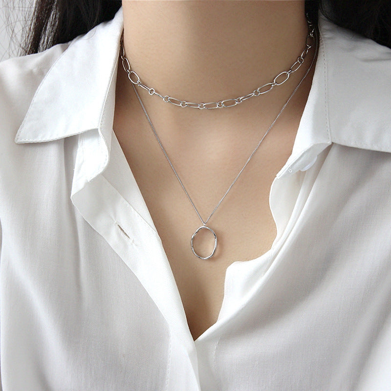 Model wearing silver irregular oval pendant necklace layered with chain choker, wholesale 925 silver jewelry for minimalist style lovers