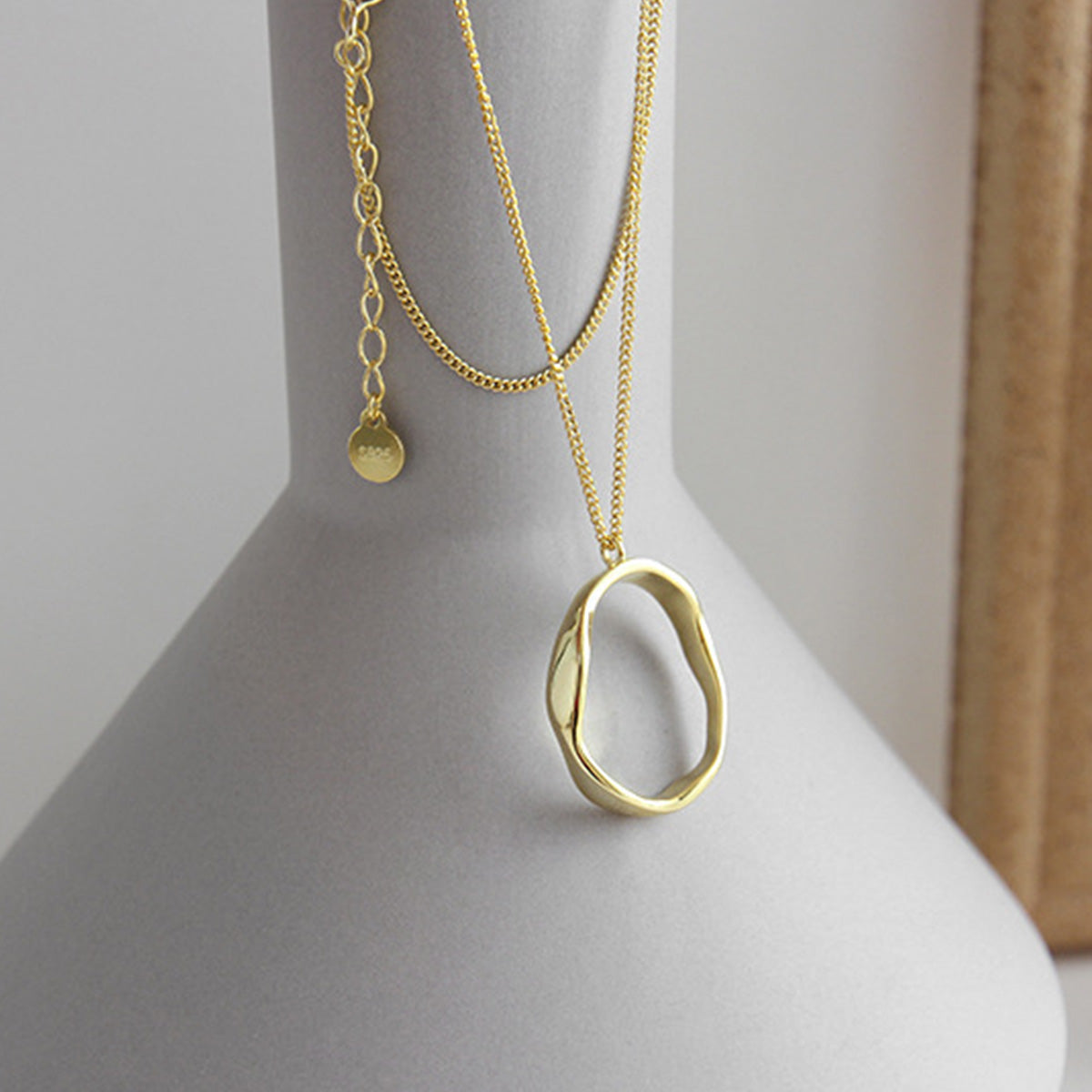 Gold irregular oval pendant necklace on a display, wholesale silver 925 jewelry with modern geometric design