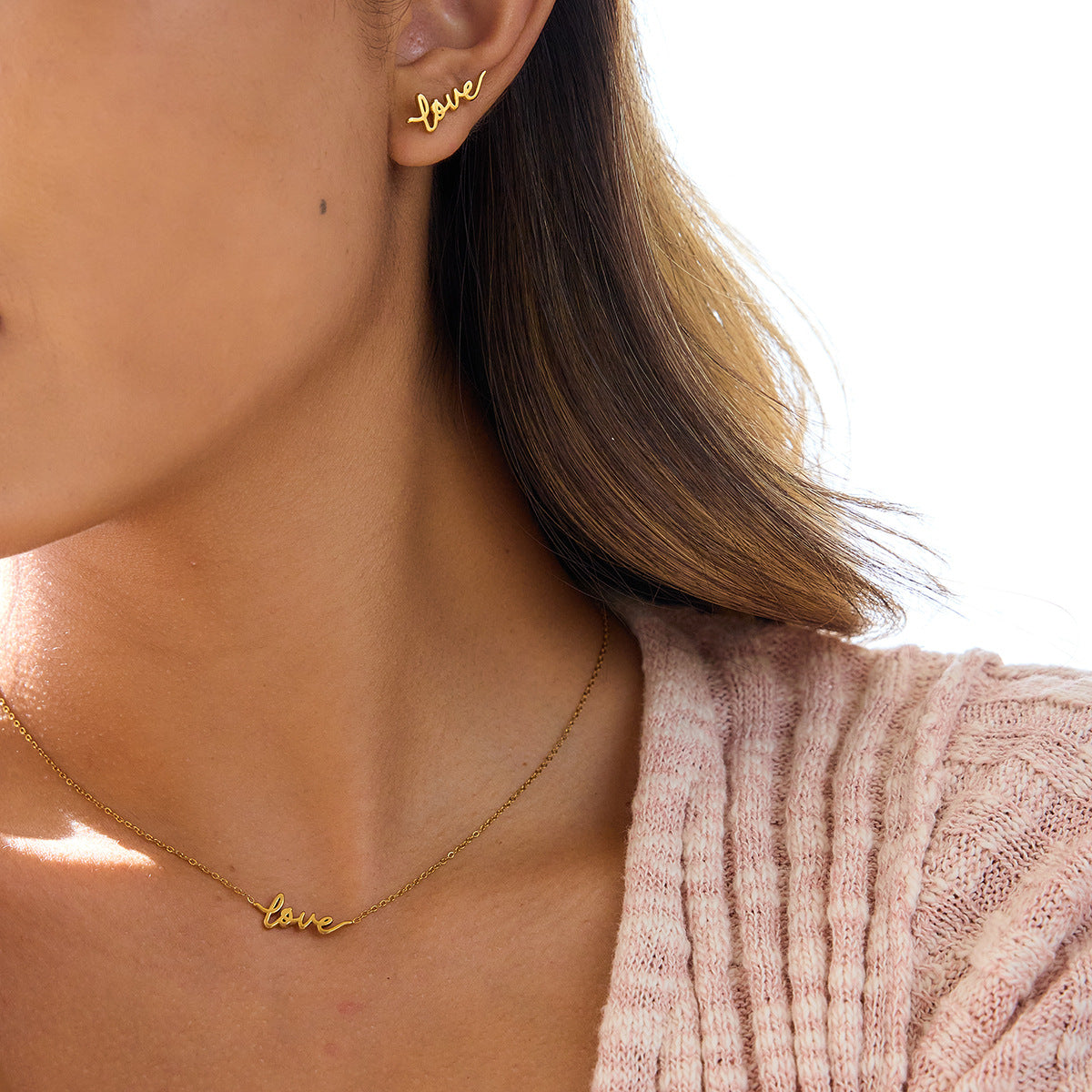 Model wearing gold stainless steel love letter stud earrings