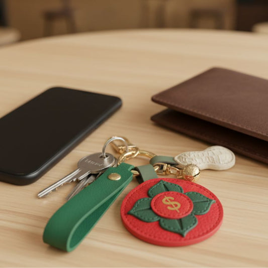 Lifestyle image of red PU leather persimmon keychain with wallet, smartphone, and keys on wooden table