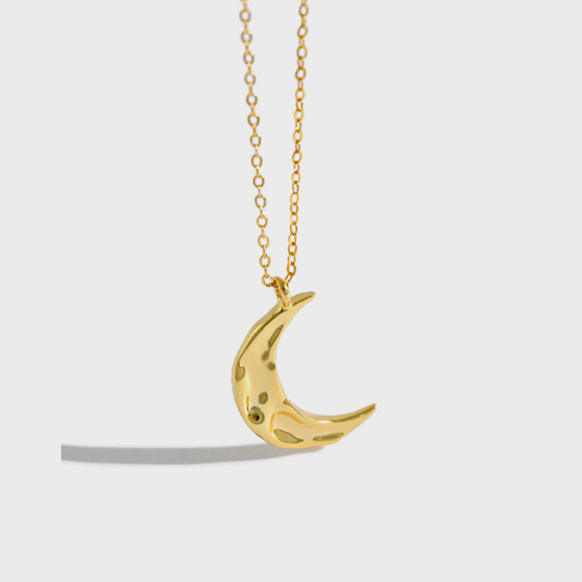 Silver and gold crescent moon necklaces displayed on a fabric background, perfect for minimalist jewelry wholesale collections.