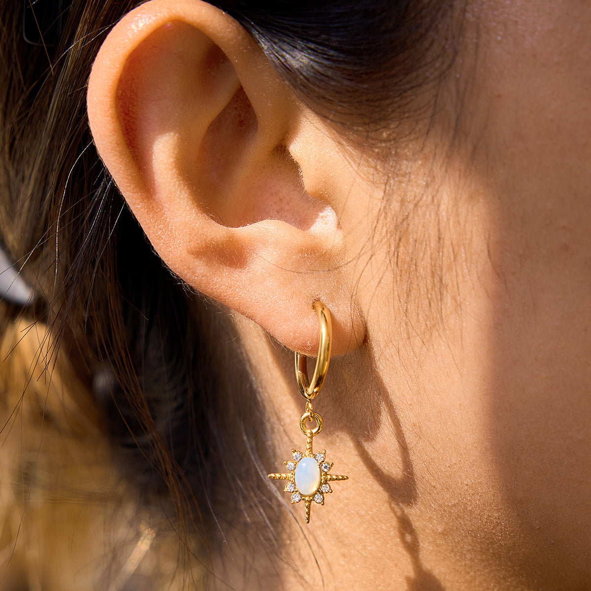 model wearing gold opal star drop hoop earrings stainless steel