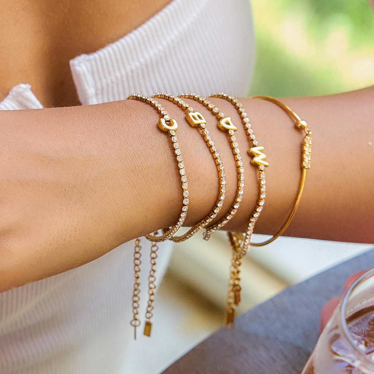 Close-up of customized gold initial bracelets in stainless steel, perfect for boutique gift and personalized wholesale jewelry