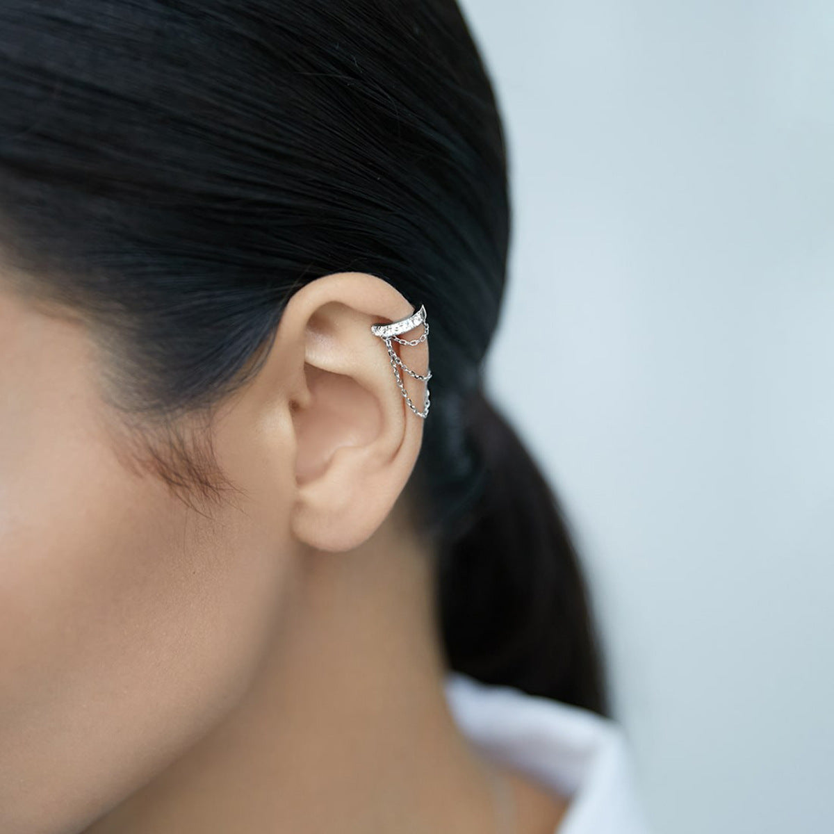 Wholesale 925 sterling silver chain ear cuff earrings with CZ stones, non-pierced adjustable clip-on design for women, shown worn on ear