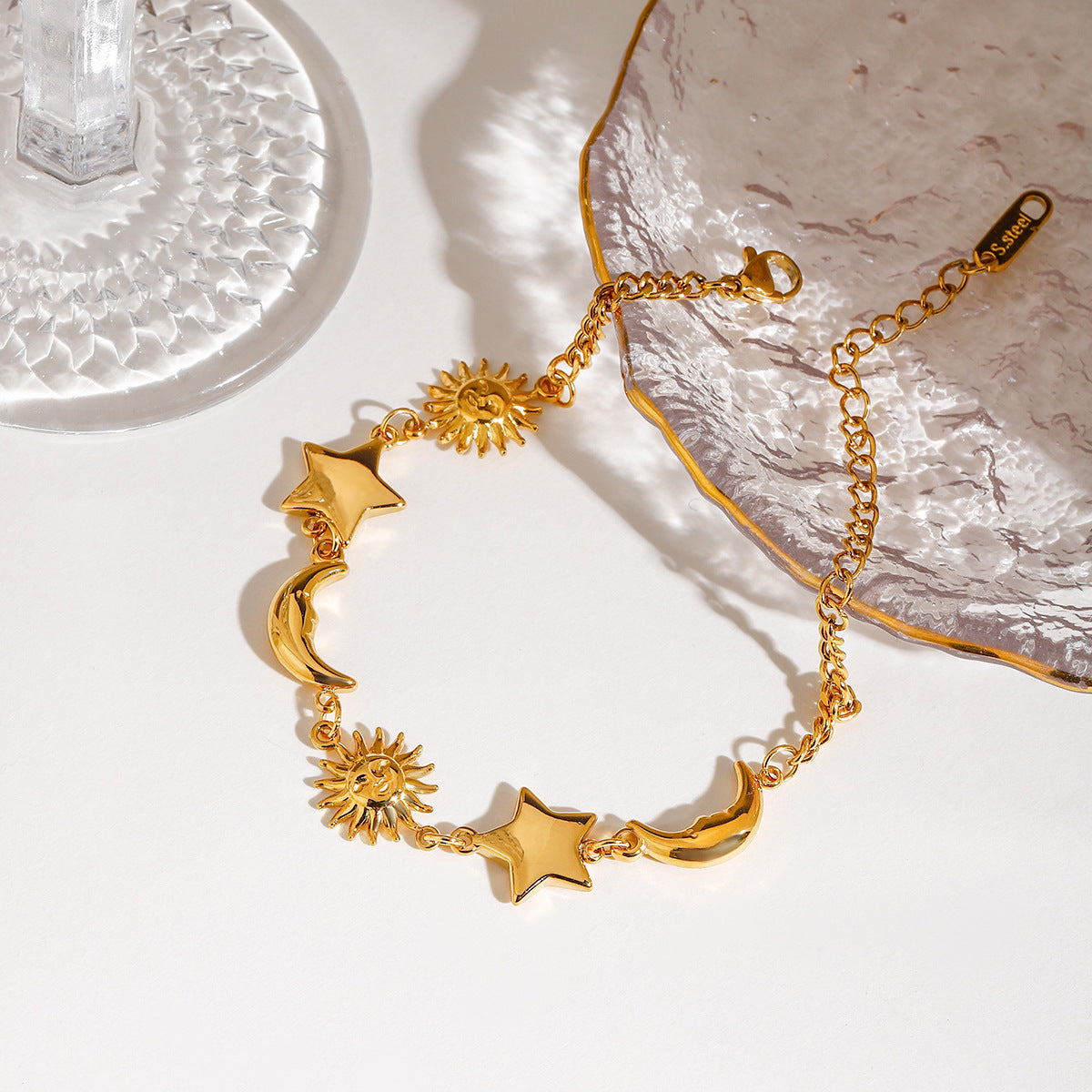 Close-up of gold stainless steel moon star sun bracelet with celestial charms for women