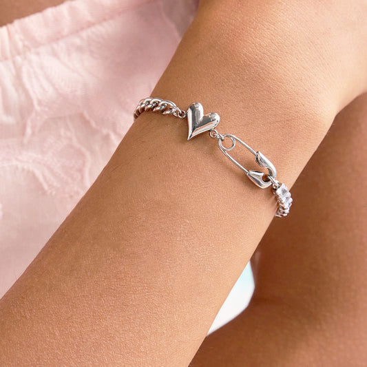 Cubic zirconia tennis bracelet with heart charm and safety pin detail, worn as a Gift for Girlfriend Bracelet. A perfect match for Wholesale CZ Bracelets and modern bridesmaid jewelry sets.