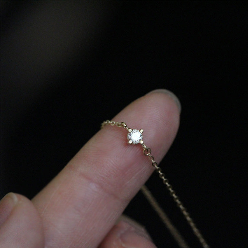Single sparkling round cut cubic zirconia gold chain bracelet close up on finger demonstrating fine craftsmanship