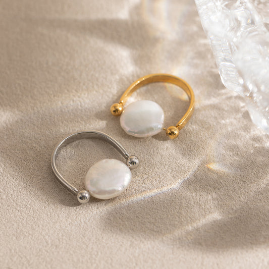 Gold and silver tone open cuff rings with pearl style center on neutral background