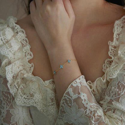 Model wearing dainty gold chain bracelet with blue cz clovers on wrist