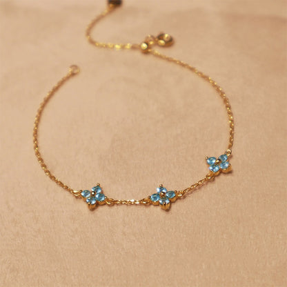 Flat lay of 18k gold plated silver clover bracelet with blue cubic zirconia stones