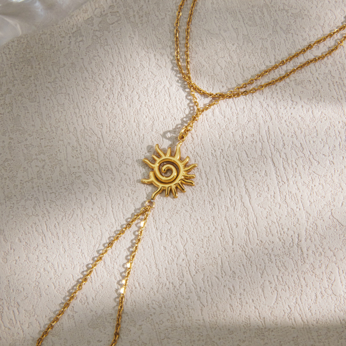 Close view of an 18K gold plated spiral sun charm hand chain bracelet