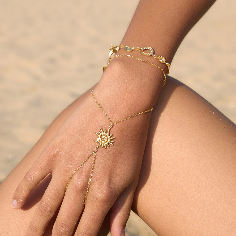 Gold celestial sun finger bracelet with a delicate wrist chain and hand chain design