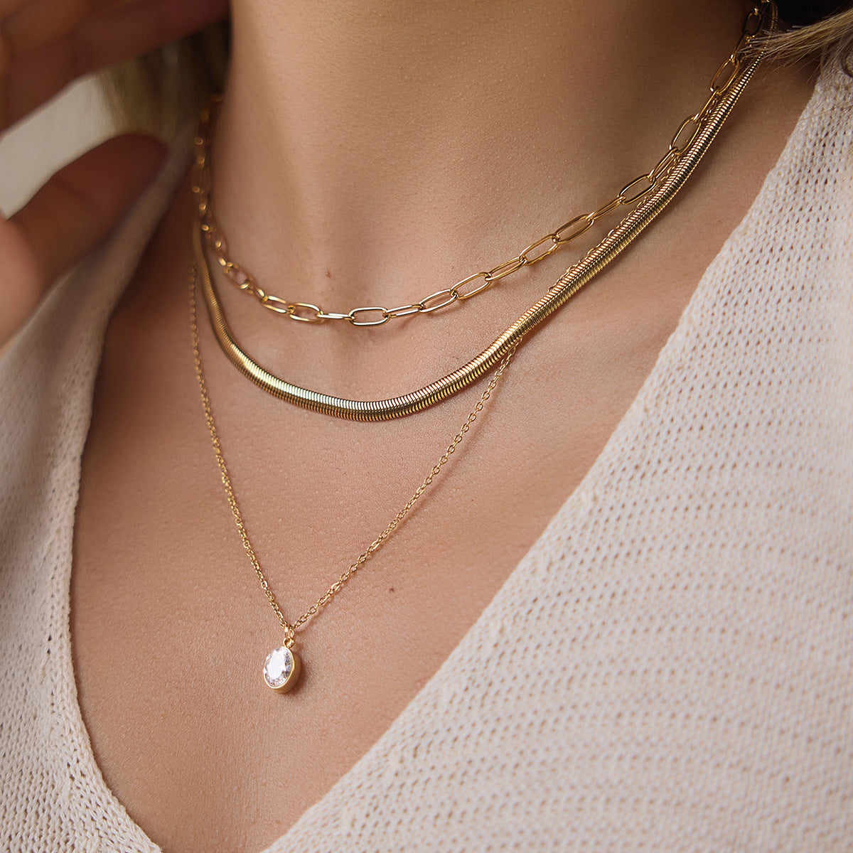Front view of an 18K gold plated layered necklace worn with a sleeveless top